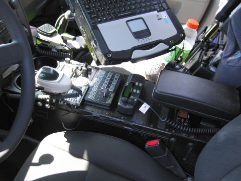 1991 Ford LTD Crown Victoria - Interior of a police vehicle showing a rugged Panasonic-style laptop, radio control head and console controls beside the seat.