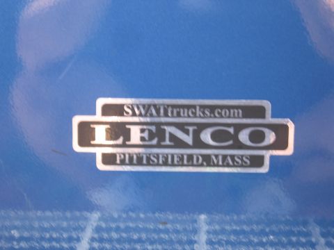 1991 Ford LTD Crown Victoria - chrome Lenco 'SWATtrucks.com / Pittsfield, Mass' manufacturer badge plate resting on a blue tarp.