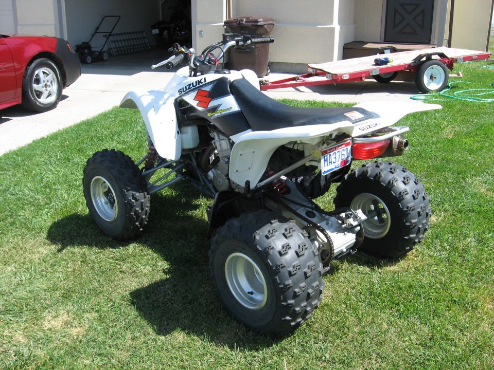 White Suzuki sport ATV quad parked on grass in a driveway with plate M937BV