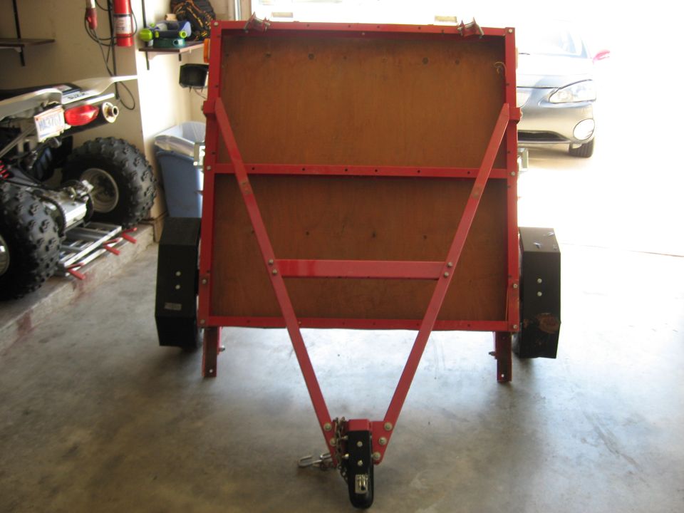 Red folding utility trailer standing upright in a garage