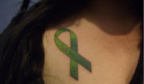 1986 Ford Bronco - Tattoo of a green ribbon with text on the back of a neck.