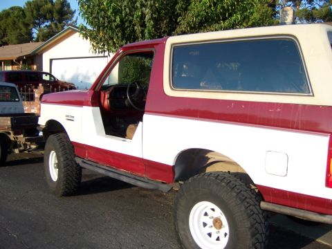 1991 Ford Bronco - This modified Ford Bronco, likely from the late 1980s, has its driver's door removed and is hitched to a trailer.