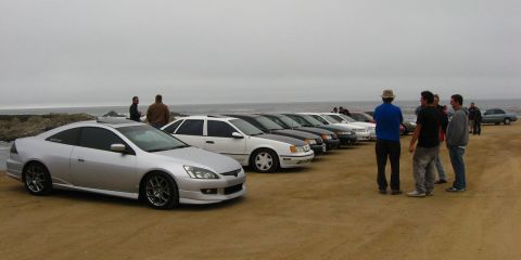 2003 Ford Taurus - A silver Honda Accord coupe on aftermarket multi-spoke wheels sits at the head of a long line of parked sedans on a sandy oceanfront lot, w…