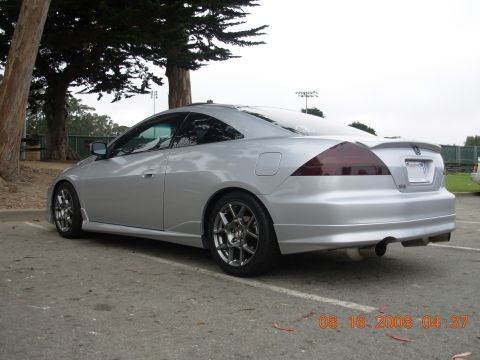 1995 Ford Taurus - A silver coupe is parked outdoors with trees and a fence in the background.