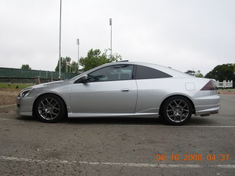 1995 Ford Taurus - A silver coupe is parked on asphalt, showing its side profile and custom wheels.