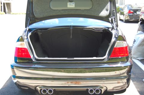 2002 BMW M3 - Rear view of a black BMW sedan with its trunk open, revealing the interior and dual exhaust pipes.