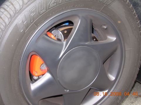1995 Ford Taurus - Close-up of a car's wheel and tire, with an orange brake caliper peeking through the spokes.