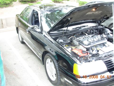 1995 Ford Taurus - 1995 Ford Taurus SHO engine bay and interior visible with hood open.