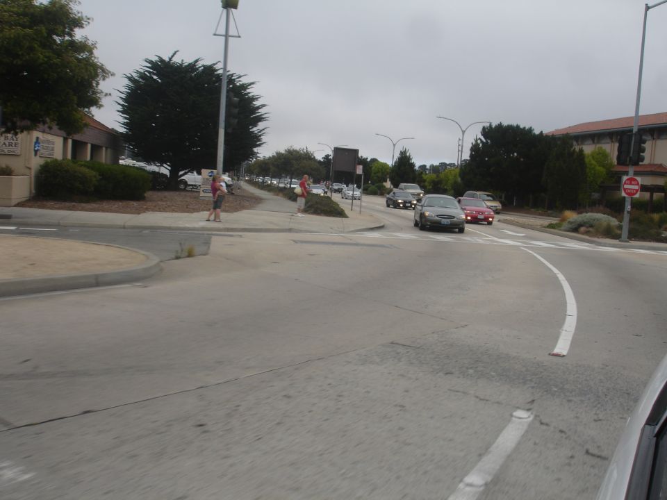 Cars driving on a road with a sidewalk and buildings nearby