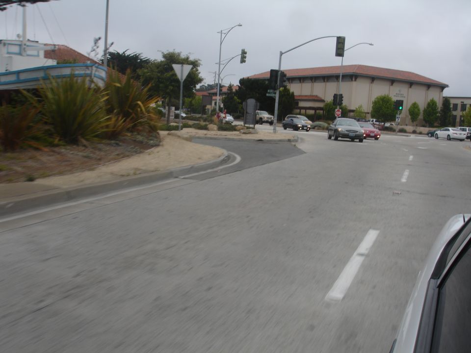 Cars driving on a cloudy day near a building and a boat-shaped structure