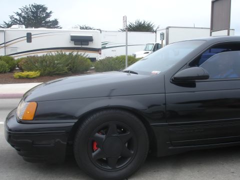 1990 Ford Taurus - A black 1990 Ford Taurus sedan is seen from the front quarter angle.