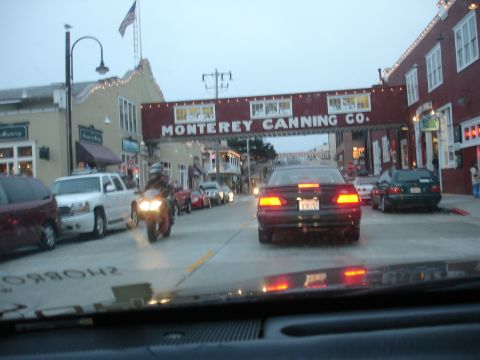 1990 Ford Taurus - A black sedan drives down a street in Monterey, California, under the historic Monterey Canning Co. sign.