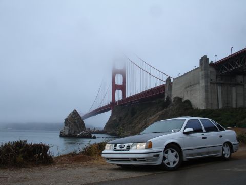 1990 Ford Taurus - 1990 Ford Taurus parked with the Golden Gate Bridge visible in the background.