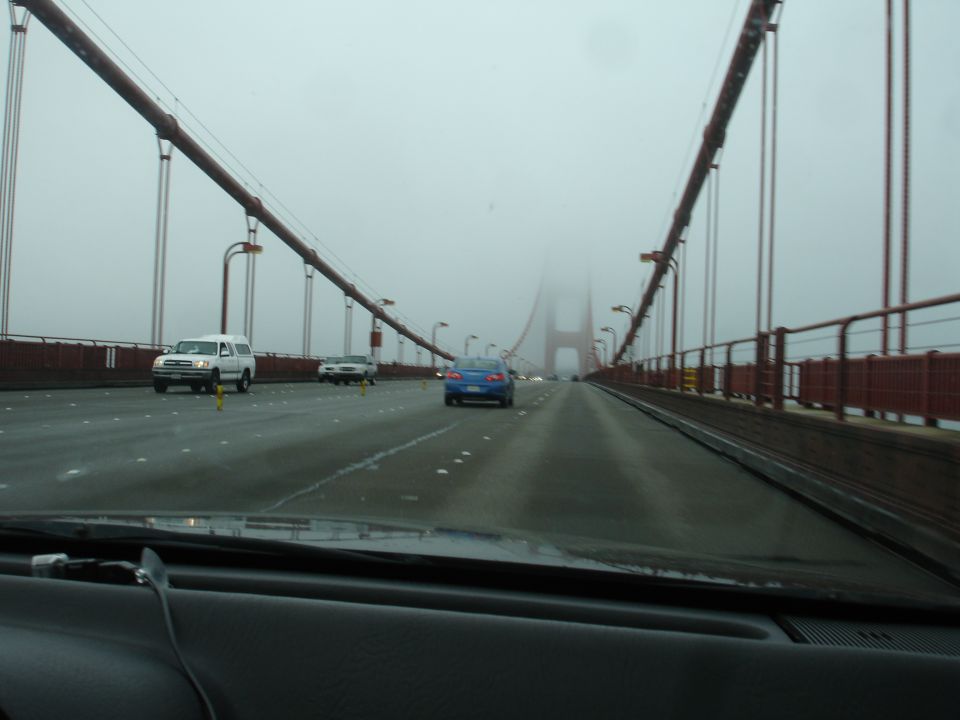 Driving across the Golden Gate Bridge on a foggy day, with other cars on the road