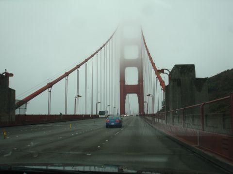 1990 Ford Taurus - A blue sedan is seen driving on the Golden Gate Bridge amidst heavy fog.