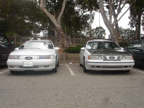 1990 Ford Taurus - Two white 1990 Ford Taurus sedans are seen from the front in a parking lot.