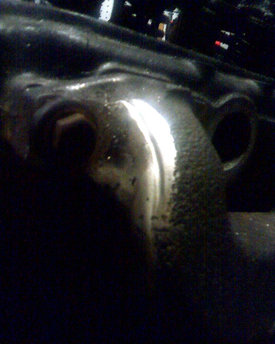 Close-up of a greasy, metallic engine component with a bolt head visible