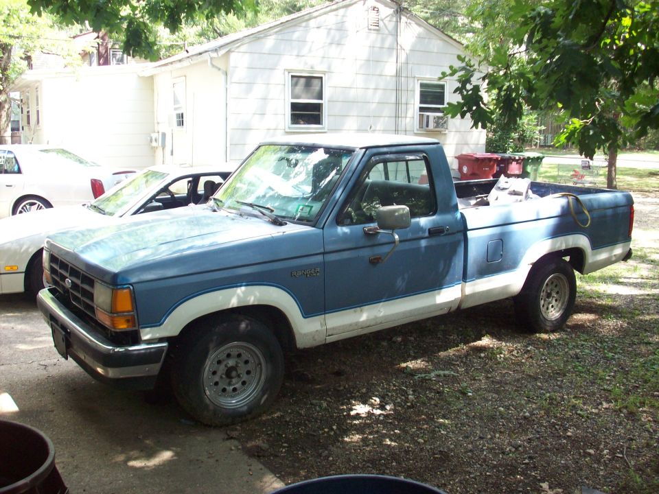 Faded two-tone blue and white Ford Ranger regular-cab pickup parked on gravel