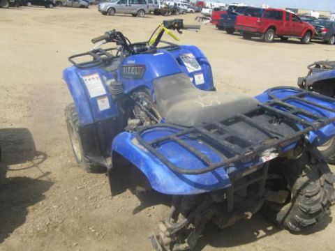 2003 Yamaha GRIZZLY 660 - A blue 2003 Yamaha GRIZZLY 660 ATV is parked in a lot with other vehicles.