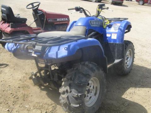 2003 Yamaha GRIZZLY 660 - A blue 2003 Yamaha GRIZZLY 660 ATV is parked outdoors next to a red riding mower.