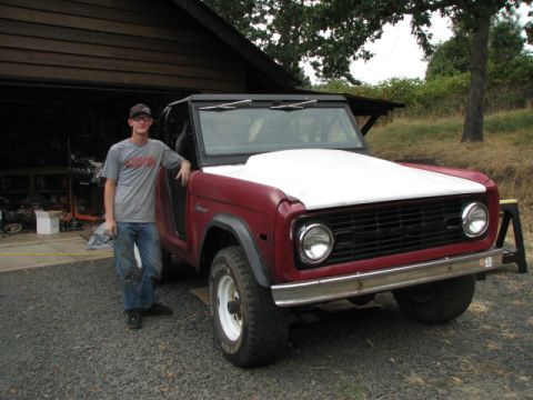 1968 Ford Bronco - A red 1968 Ford Bronco is parked outside a garage with a person standing beside it.