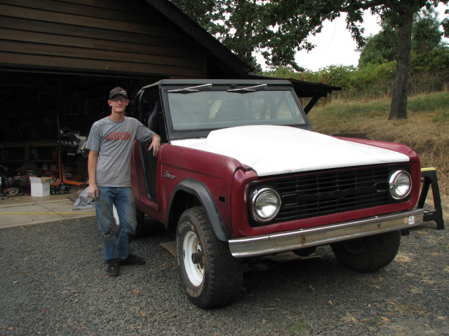 1968 Ford Bronco with a white hood and a person standing next to it