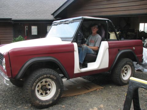 1968 Ford Bronco - A person sits in the driver's seat of a classic Ford Bronco, which appears to be undergoing some work.