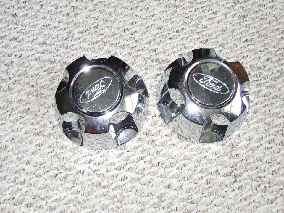 Two chrome Ford center caps on carpet