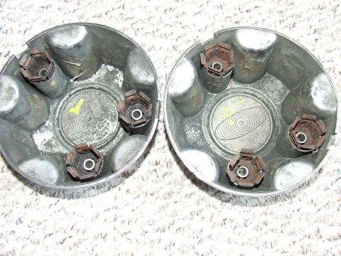 2003 Ford Crown Victoria - Two used, silver-colored hubcaps are shown from the inside. Each hubcap has a circular metal center with embossed text and a yellow marking.