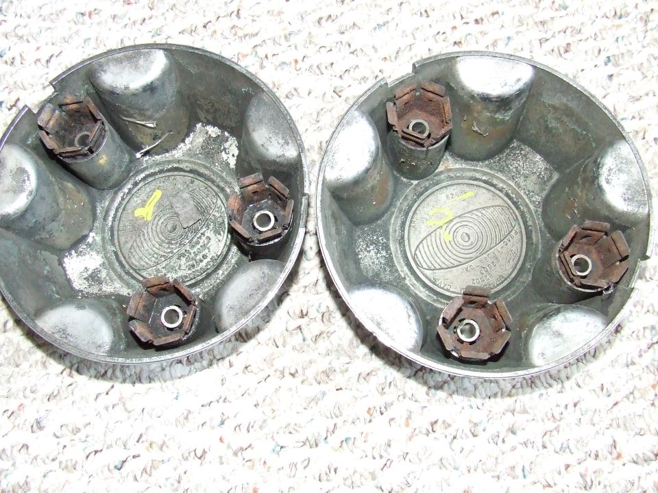 Two silver hubcaps viewed from the inside, showing metal clips and embossed text.