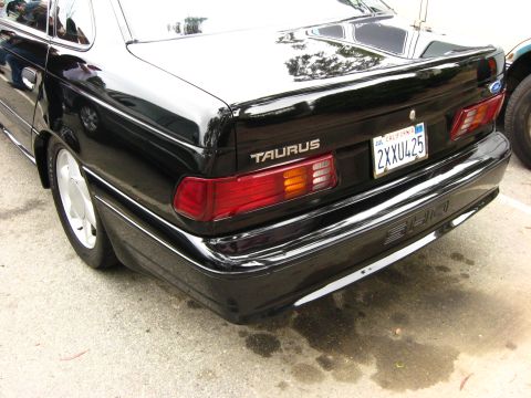 2003 Ford Taurus - The rear driver's side quarter of a black sedan is shown, featuring a "TAURUS" badge, a California license plate reading "2XXU425", and "SH…
