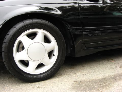 2003 Ford Taurus - Close-up of the front wheel on a black Ford Taurus SHO, fitted with a white five-spoke alloy wheel and a Bridgestone Potenza RE-01R tire. T…