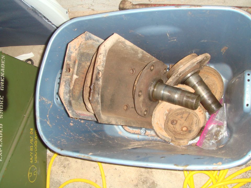 Rusty vehicle parts in a blue bin next to a green storage container.