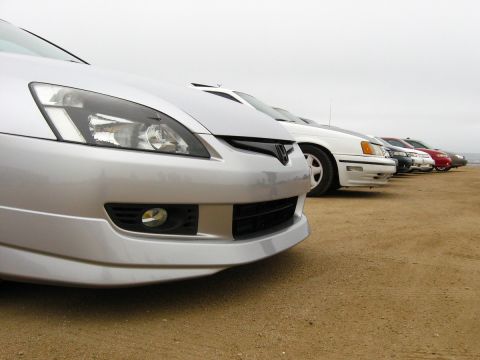2003 Ford Taurus - Low-angle front view of a silver sedan with several cars lined up behind on a dirt lot.