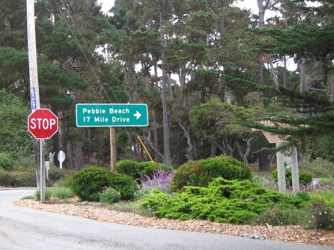 2003 Ford Taurus - A green highway guide sign reading "Pebble Beach 17 Mile Drive" with a right arrow stands beside a red STOP sign at a wooded roadside inter…