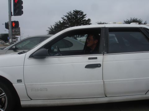 1990 Ford Taurus - A white sedan is seen from the side on a cloudy day.
