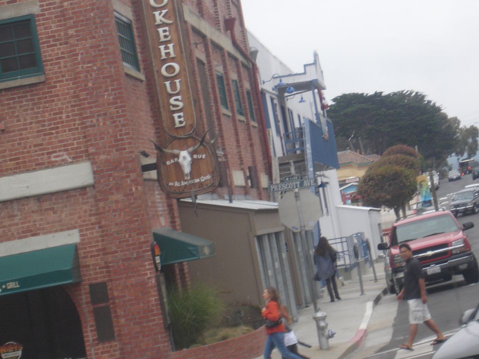 Red pickup truck parked on street next to brick building with Smokehouse sign.