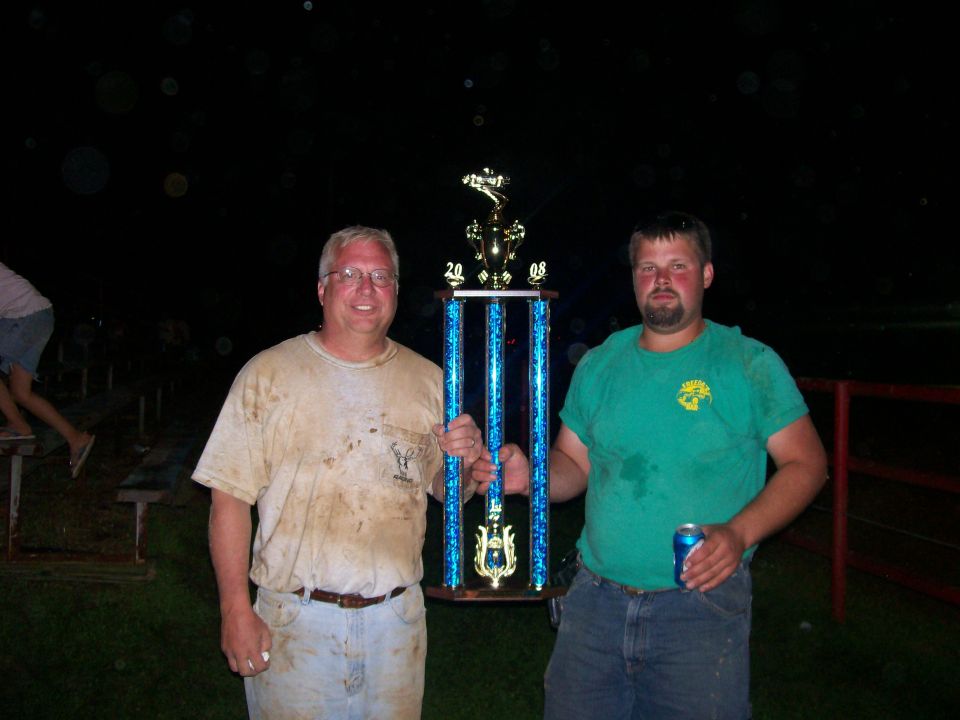 Two men holding a blue-columned 2008 trophy at night