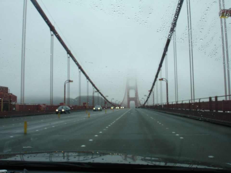 View from inside a car driving on the Golden Gate Bridge in fog and rain.