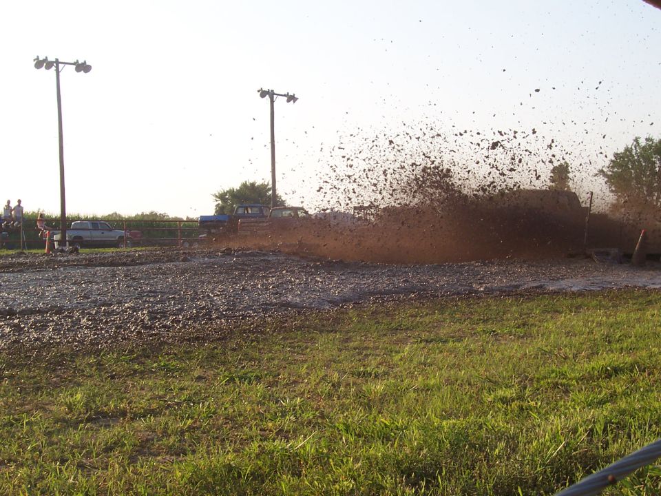 Pickup truck creating a large mud splash on a muddy track.