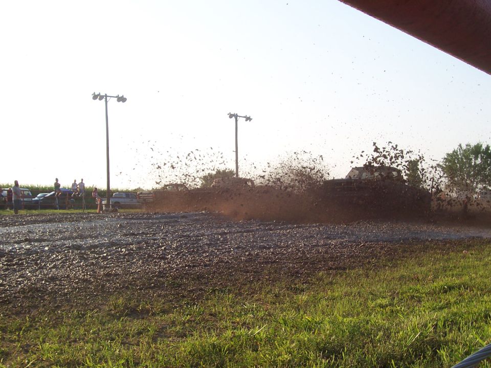 Muddy Dodge 1500 truck splashing through a mud pit.