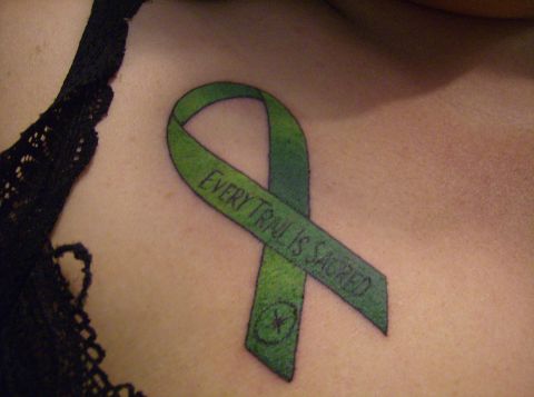 1986 Ford Bronco - A close-up tattoo of a green ribbon with the text "EVERY TRAIL IS SACRED" is visible on a person's chest, partially obscured by black lace.