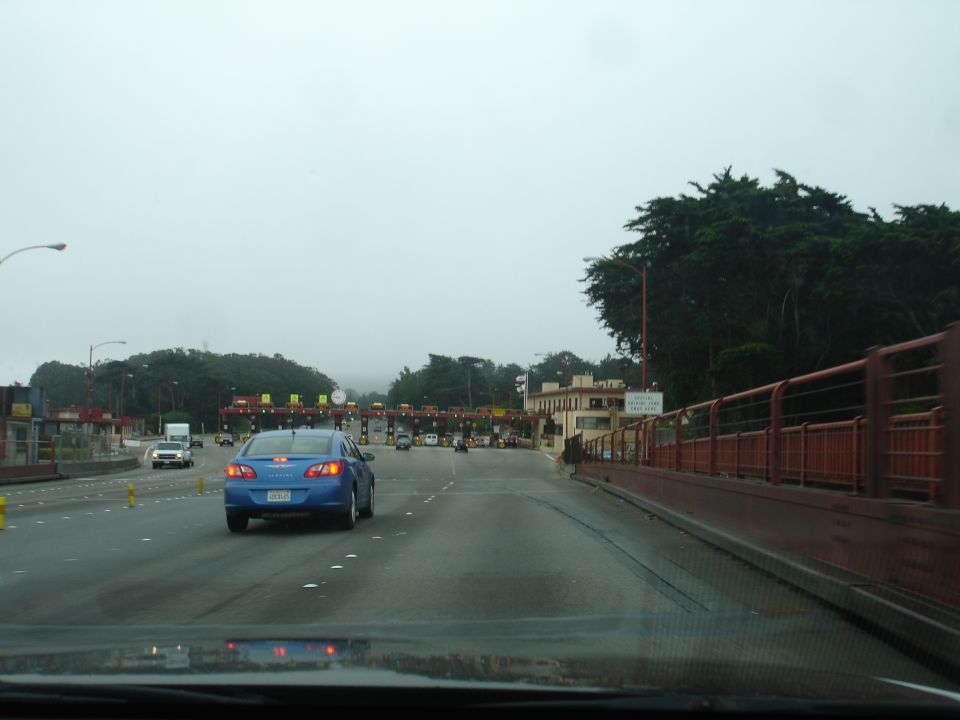 Blue sedan at a toll plaza.