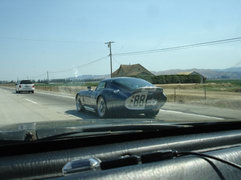1990 Ford Taurus - A blue Shelby Cobra Daytona Coupe replica is seen on the highway, with a white SUV in the distance.