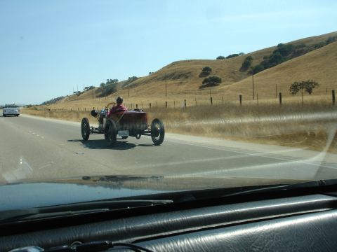 1990 Ford Taurus - A vintage hot rod drives down a highway with a white car in the distance.