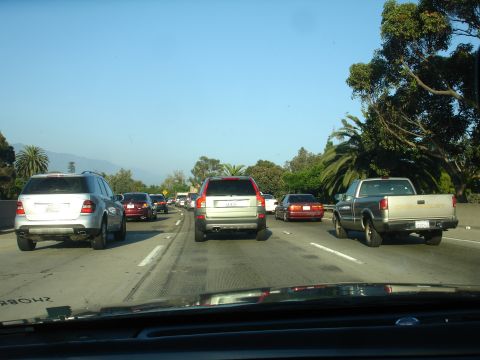 1990 Ford Taurus - Multiple vehicles are stuck in a traffic jam on a sunny day.