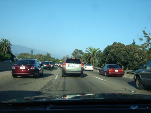 1990 Ford Taurus - A line of cars are stuck in traffic on a highway under a clear blue sky.