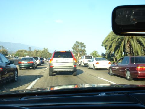 1990 Ford Taurus - Cars are stuck in traffic on a highway under a clear blue sky.