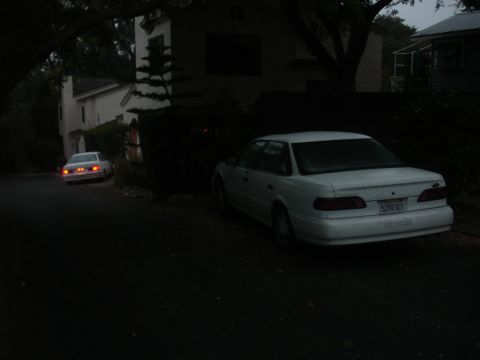 1990 Ford Taurus - A white 1990 Ford Taurus is parked on the street, with another car visible in the distance.
