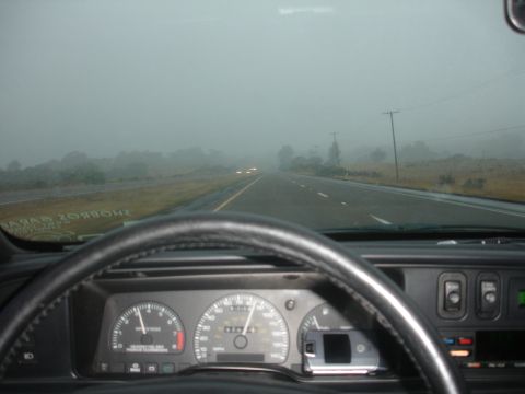 1990 Ford Taurus - Driving through heavy fog on a highway, visibility is extremely limited.